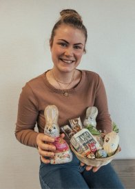 Faire Ostern Projektbeauftragte Kim Lachmann hat Schoko-Osterhasen und weitere Fairtrade-Süßigkeiten in der Hand.