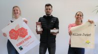 Faire Woche Drei Azubis zeigen ein Plakat zur fairen Woche, Jutebeutel und fair gehandelte Produkte.