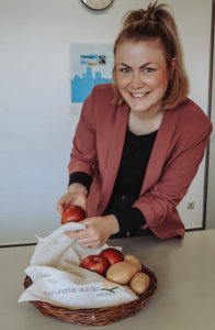 Fair trade Obstbeutel Projektbeauftragte Kim Lachmann zeigt Obstbeutel aus fair gehandeltem Material und packt Äpfel hinein.