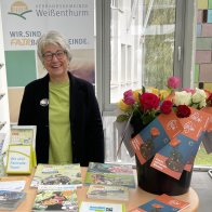 Faire Woche Stand Gaby Kohns steht an einem Fairtrade-Stand mit Rosen und Info-Material im Foyer des VG-Rathauses.