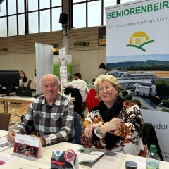 An einem Tisch vor einem Rollup des Seniorenbeirates sitzt die Seniorenbeauftragte der VG, Renate Schumann, neben dem Beiratsmitglied Herbert Nickenig.