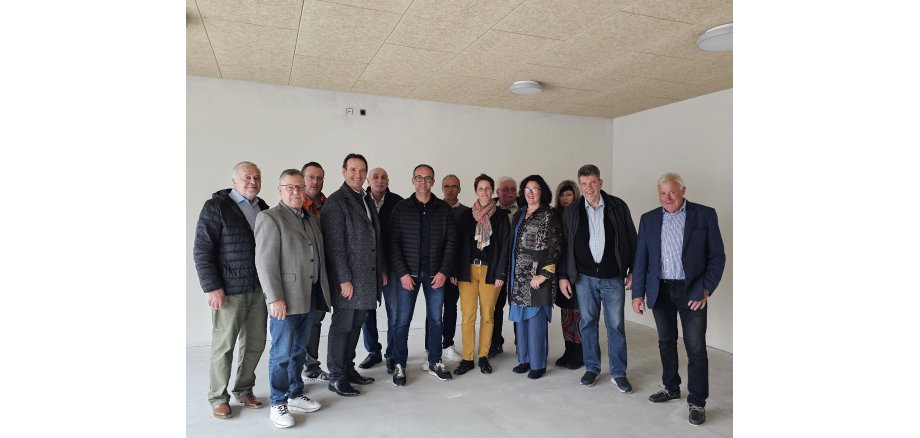 In einem Raum des Neubaus stehen alle an dem Rundgang beteiligte Personen in einem Halbkreis.