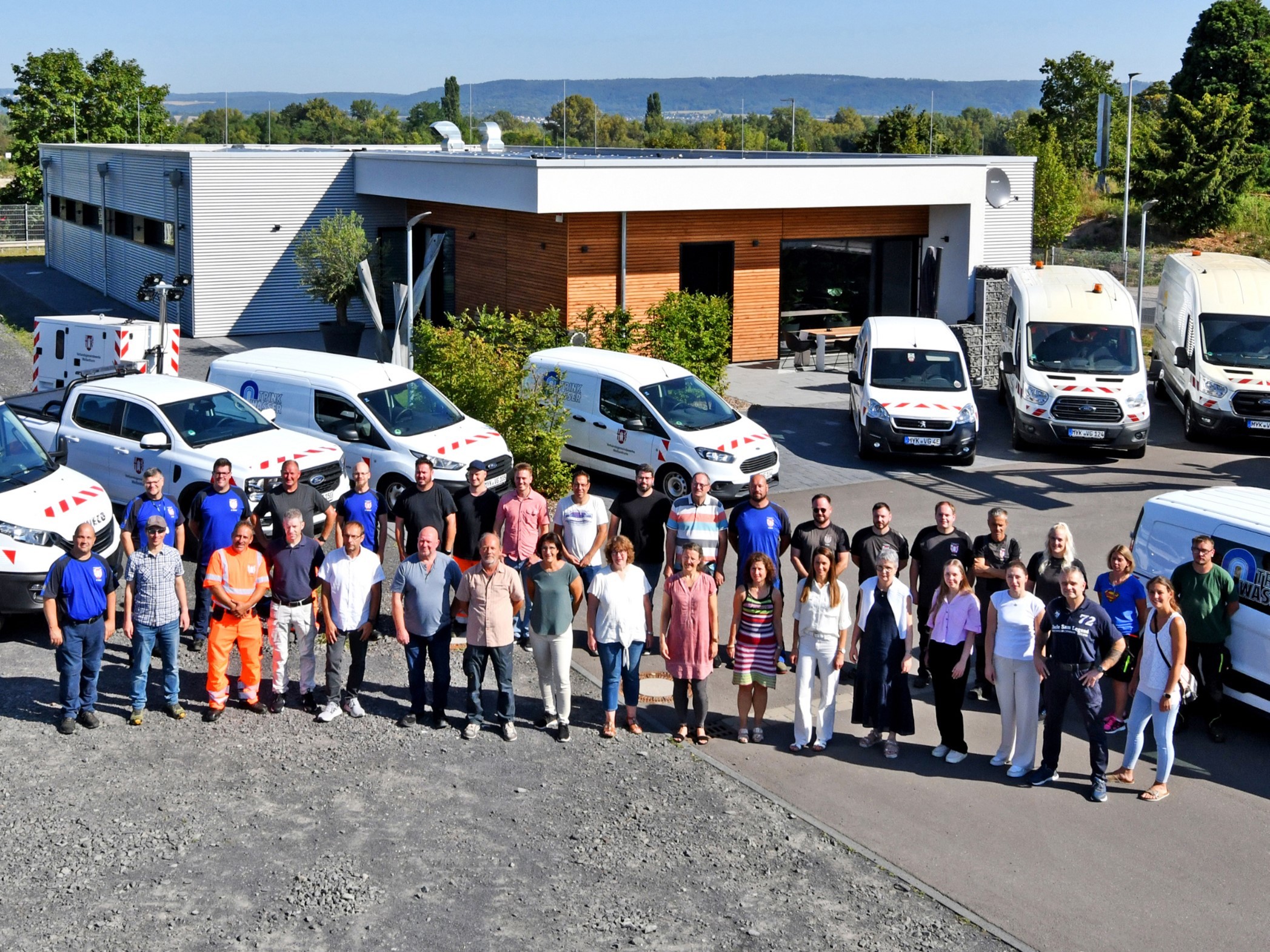 Alle Mitarbeiterinnen und Mitarbeiter der Verbandsgemeindewerke stehen vor dem neuen Betriebsgebäude in einem Halbkreis. 