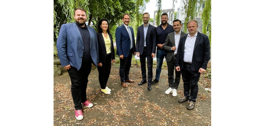 Sechs Bürgermeister und die Vertreterin des Vallendarer Verwaltungschefs stehen im Halbkreis auf einer Terrasse vor dem VG-Gebäude.
