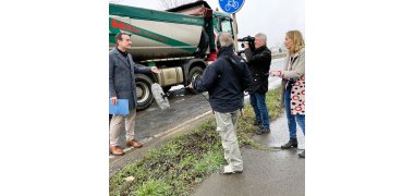 Bürgermeister Przybylla steht links am Straßenrand, hinter ihm fährt gerade ein LKW vorbei. Ihm gegenüber stehen der Kameramann, ein Tontechniker und die Redakteurin des SWR.