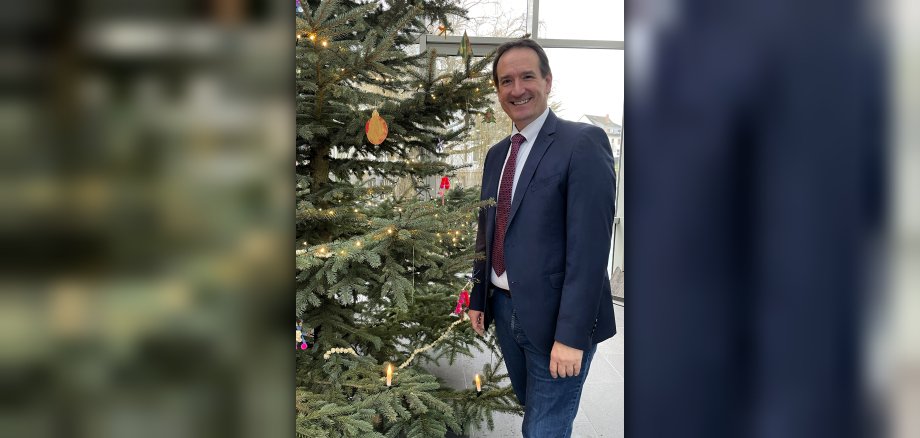 Bürgermeister Thoma Przybylla steht rechts neben dem geschmückten Weihnachtsbaum. 
