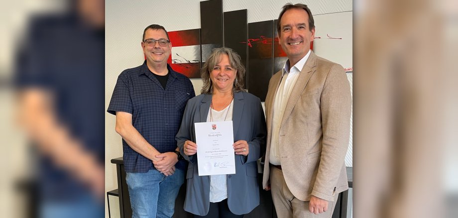 Dienstjubiläum Claudia Piske Claudia Piske steht mit ihrer Urkunde zwischen Bürgermeister Thomas Przybylla und dem Vorsitzenden des Personalrats, Marko Röser.