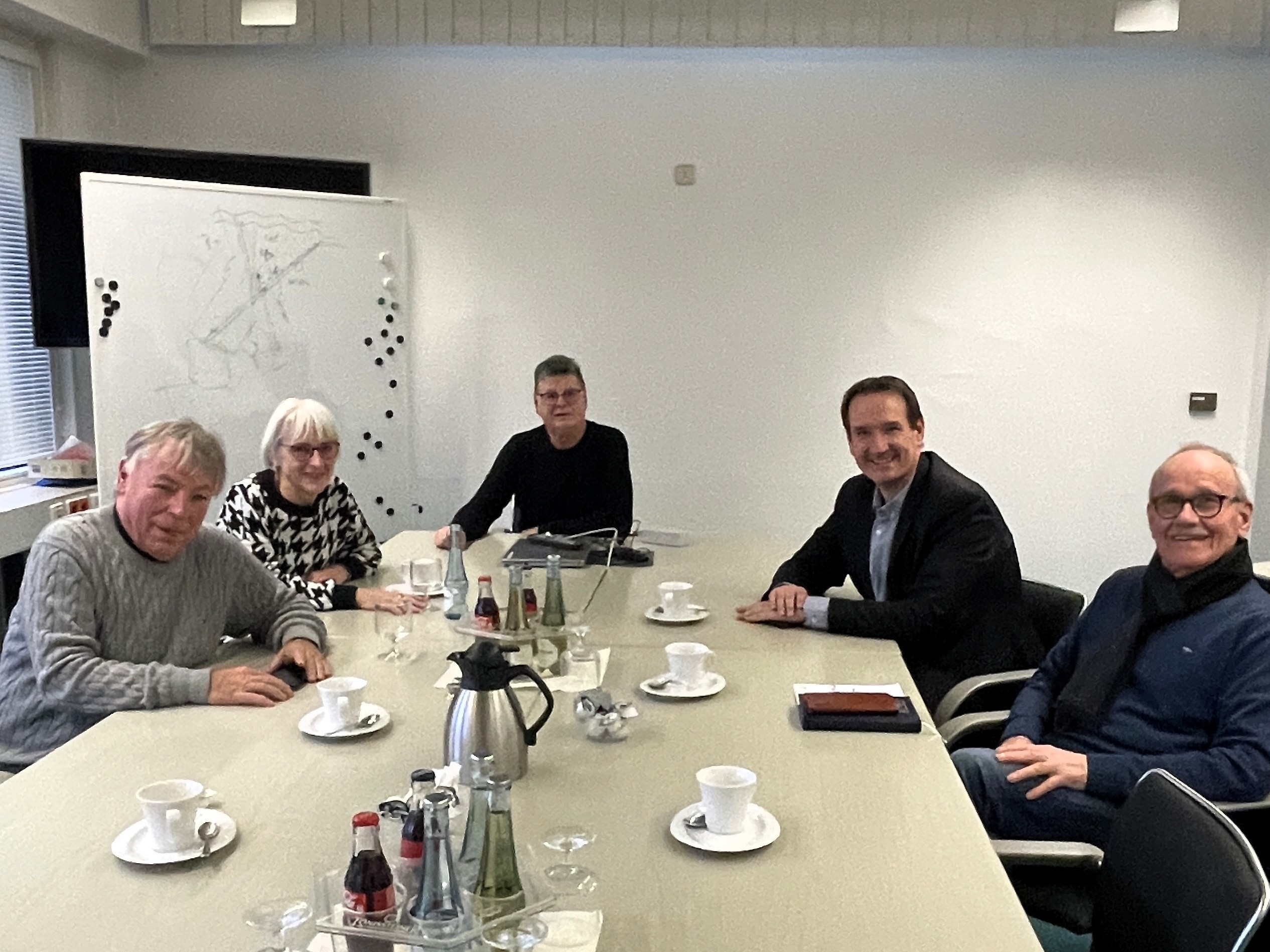 An einem Tisch mit Getränken darauf sitzen rechts der Vorsitzende des Seniorenbeirats, Hajo Reif, Bürgermeister Thomas Przybylla und gegenüber Tafel-Vorsitzender Peter Bäsch, Annette Bäsch und der 2. Vorsitzende Alfred Waurig.
