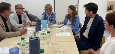 Minister Teuber bespricht sich mit Bürgermeister, Fachbereichsleiter, Kita-Leiterin und Mitgliedern des multiprofessionellen Teams. 