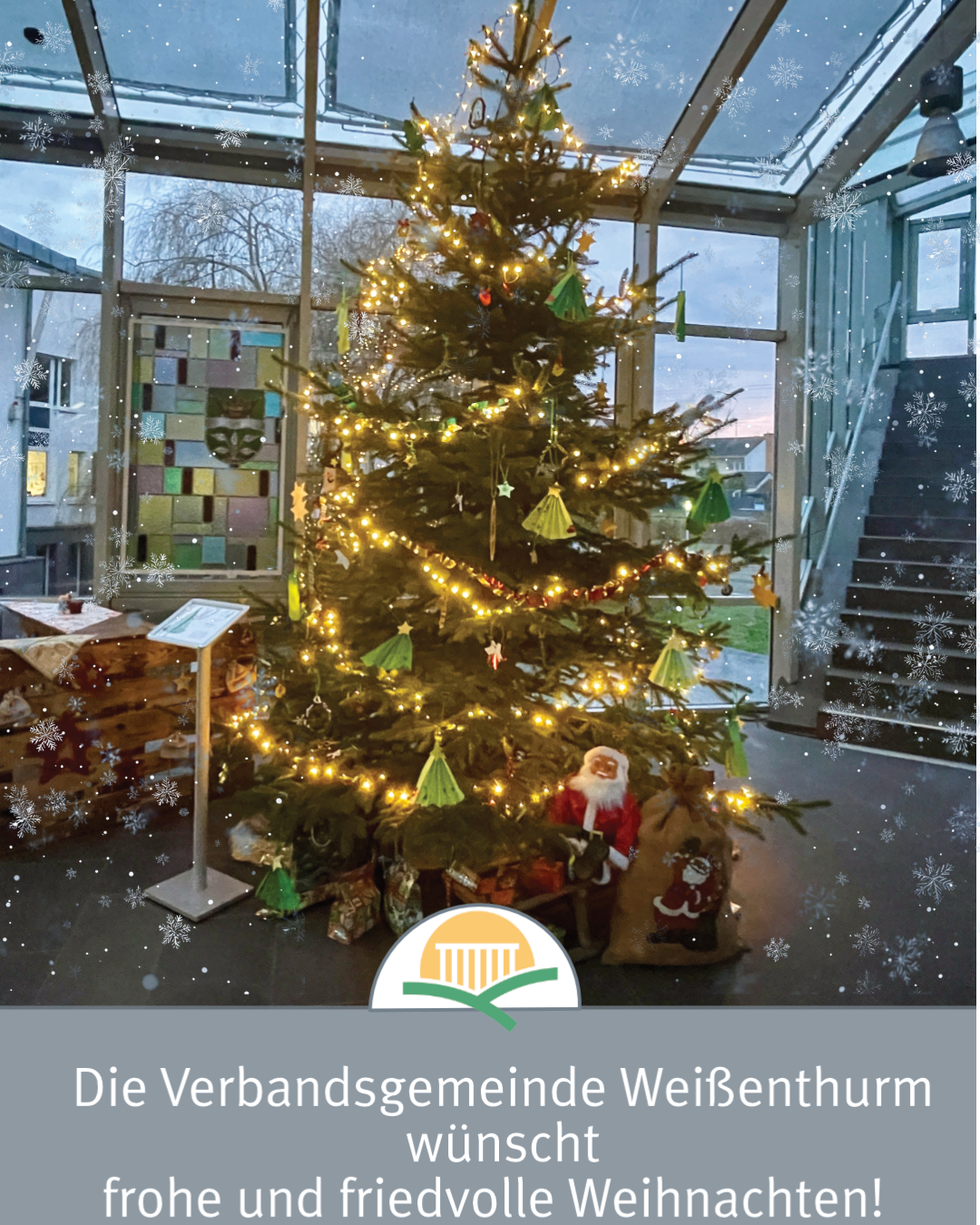 Der geschmückte Weihnachtsbaum im Foyer des Rathauses ist von Schneeflocken umgeben. 