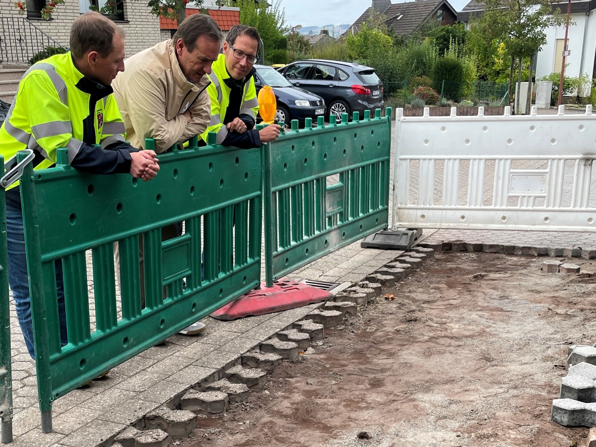 Bürgermeiste Thomas Przybylla steht mit den Mitarbeitern Reinhold Jeck und Joachim Freund an einer Absperrung, die vor einer aufgerissenen Straße steht. 