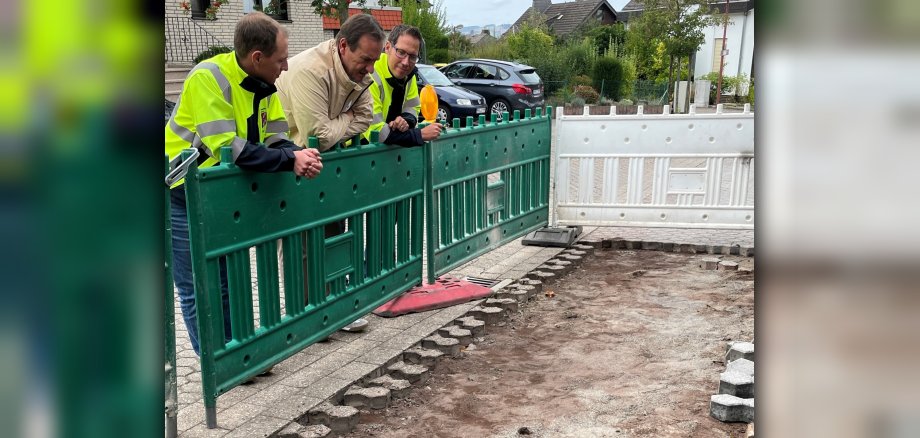 Bürgermeiste Thomas Przybylla steht mit den Mitarbeitern Reinhold Jeck und Joachim Freund an einer Absperrung, die vor einer aufgerissenen Straße steht. 