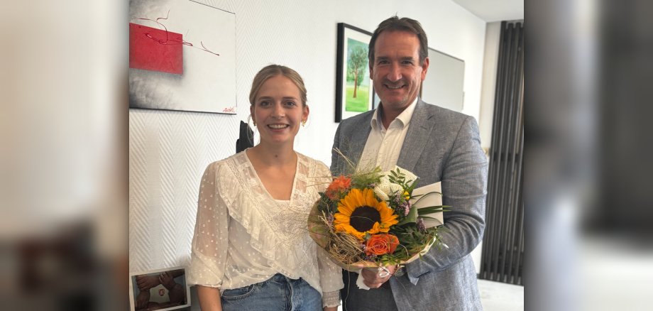 Bürgermeister Thomas Przybylla überreicht Rowena Redwanz einen bunten Blumenstrauß.