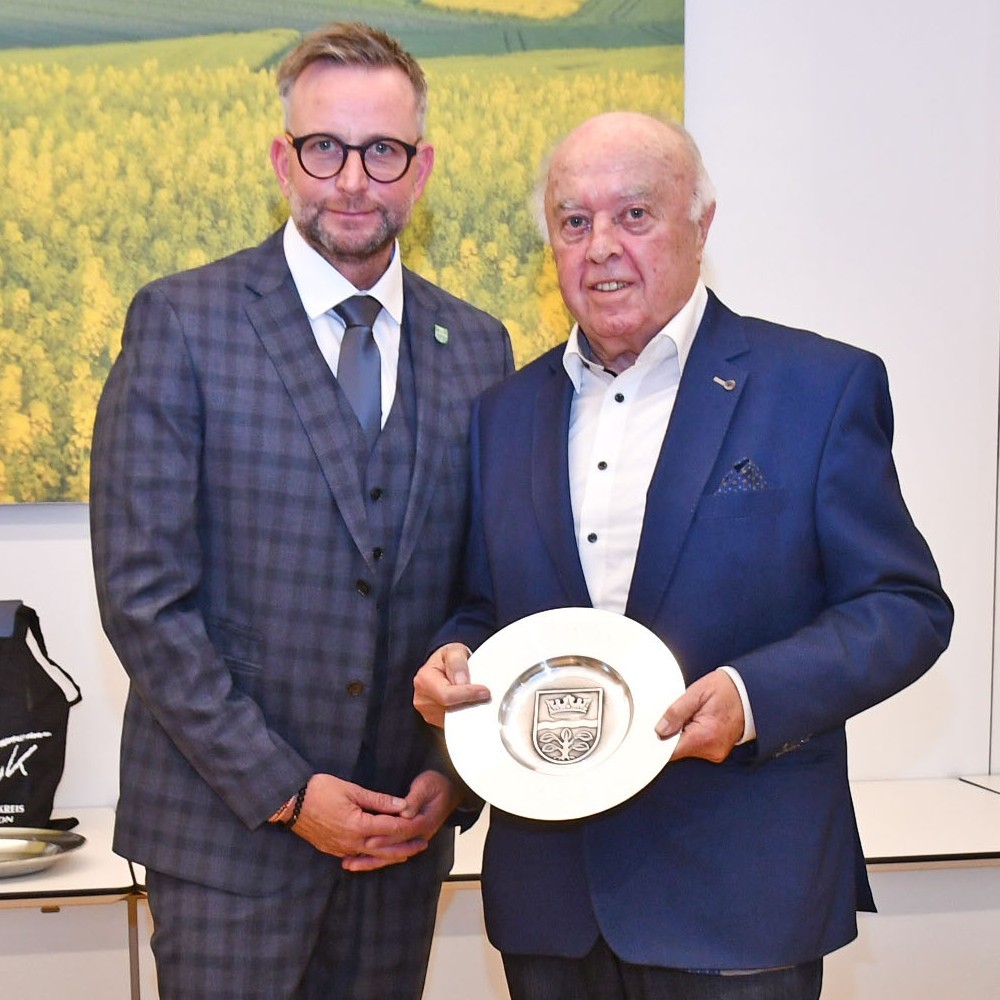 Wappenteller Herbert Nickenig Herbert Nickenig steht mit dem Wappenteller in der Hand neben Landrat Marko Boos.