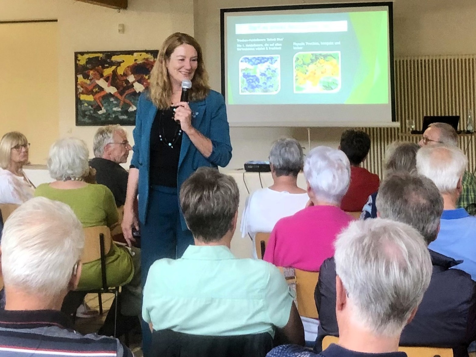 Vortrag Hochbeete Heike Boomgaarden trägt mit einem Mikrofon in der Hand dem Publikum zu Hochbeeten vor.