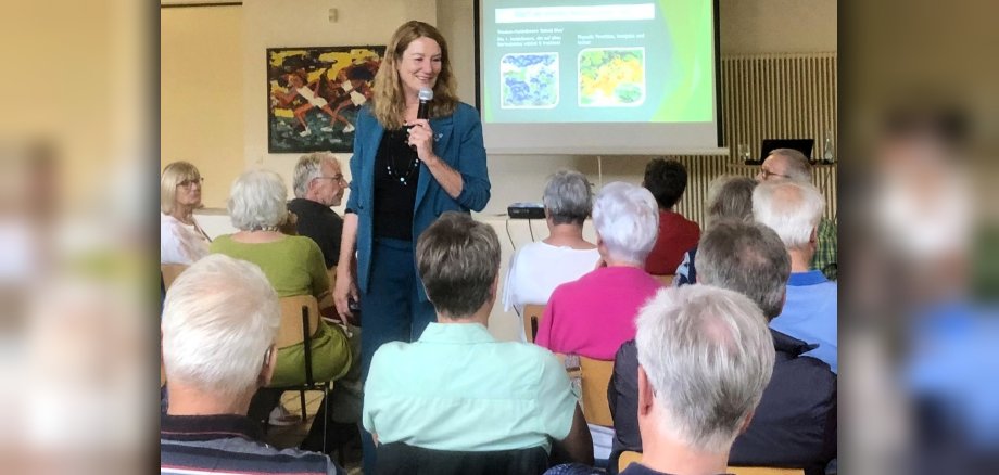 Heike Boomgaarden trägt mit einem Mikrofon in der Hand dem Publikum zu Hochbeeten vor.