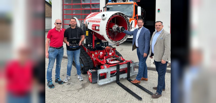 Vor dem Gerätehaus der Feuerwehr Weißenthurm stehen Wehrleiter Arnd Lenarz, sein Stellvertreter Marco Ihrlich, der Weißenthurmer Wehrführer Torsten Schnack und Bürgermeister Thomas Przybylla am Löschroboter.