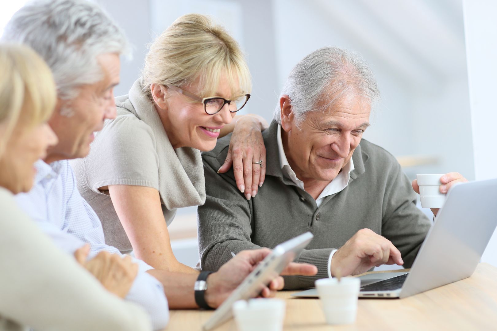 Digitalisierung ältere Menschen Eine Gruppe von Seniorinnen und Senioren sitzt an einem Laptop.