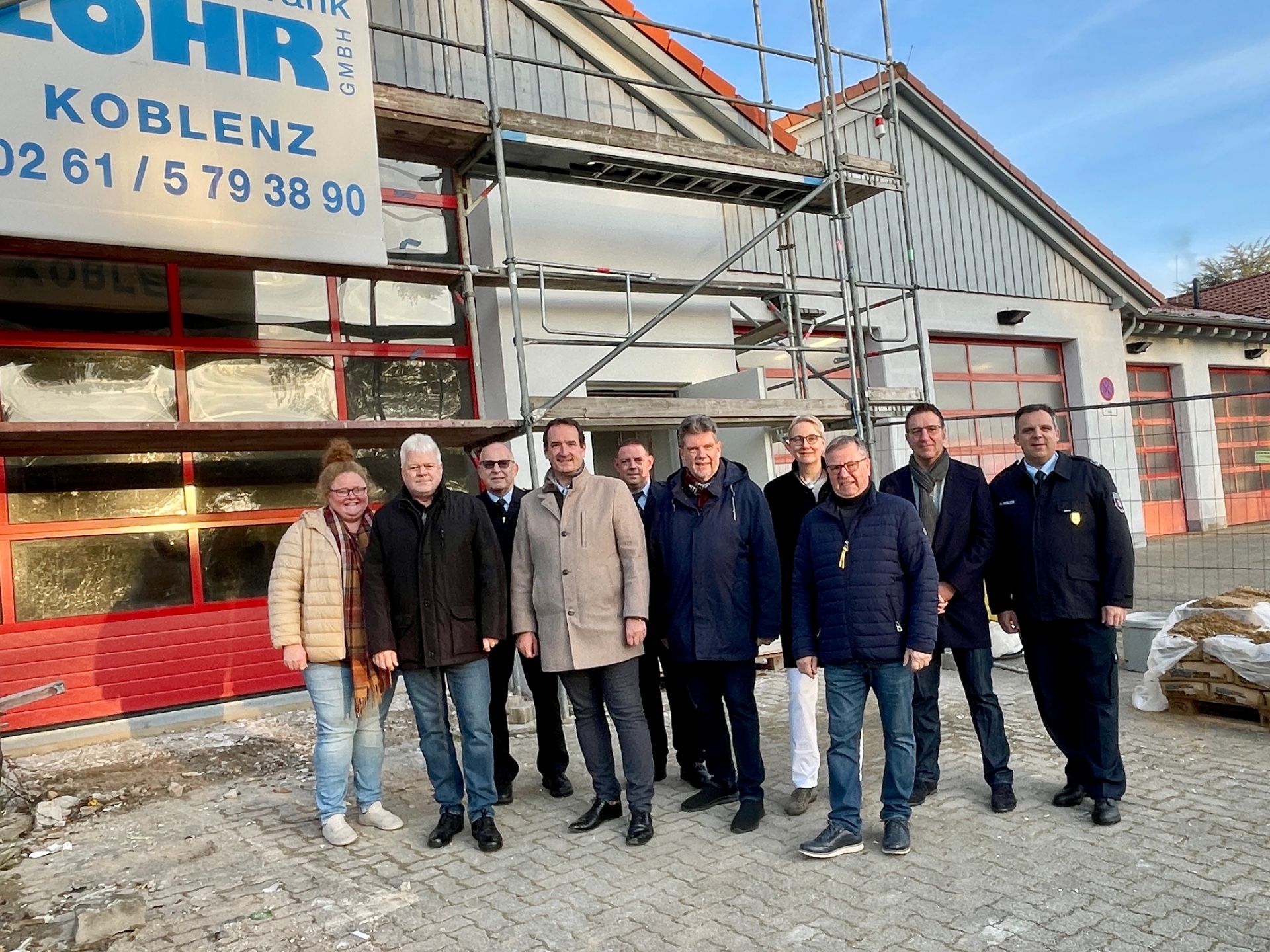 Erweiterung Feuerwehrgerätehaus Bassenheim Bürgermeister Thomas Przybylla steht mit WehrleiterArnd Lenarz, dem Bassenheimer Wehrführer Michael Röser und Mitgliedern des Ältestensrates vor dem eingerüsteten Anbau an das Feuerwehrgerätehaus.