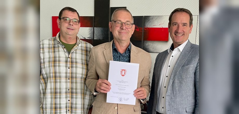 Zwischen Bürgermeister Thomas Przybylla und Personalratsvorsitzendem Marko Röser steht Stefan Maxeiner mit der Entlass-Urkunde. 