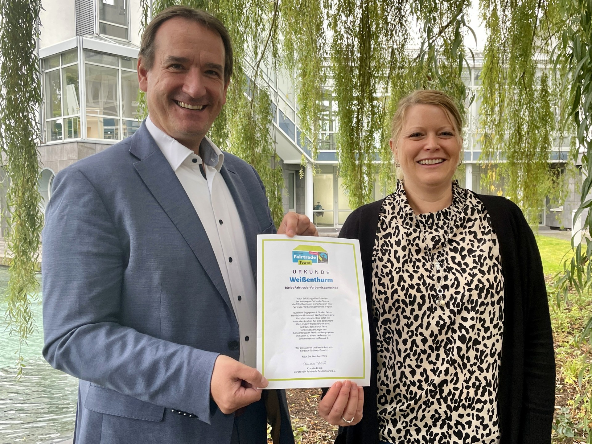 Rezertifizierung Fairtrade Bürgermeister Thomas Przybylla und Projektbeauftragte Kristina Uerz halten die Urkunde zur zweiten Rezertifizierung der VG.