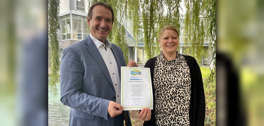 Bürgermeister Thomas Przybylla und Projektbeauftragte Kristina Uerz halten die Urkunde zur zweiten Rezertifizierung der VG.