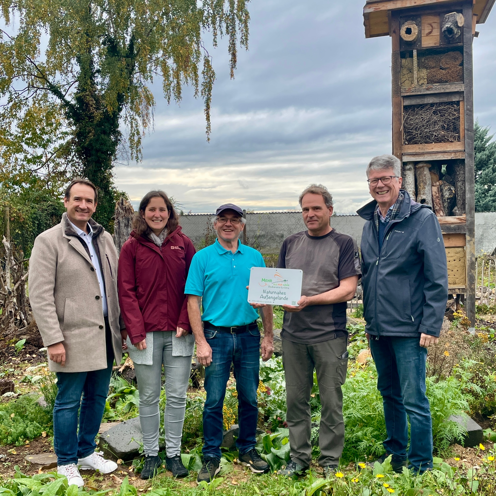 Örmser Erlebnisgarten Bürgermeister Thomas Pzrybylla, Ortsbürgermeister Norbert Bahl und Klimaschutzmanagerin Jennifer Vogt überreichen an die Initiatoren Manfred Schmid und Joachim Hommer das Schild zur Auszeichnung als naturnahes Außengelände.