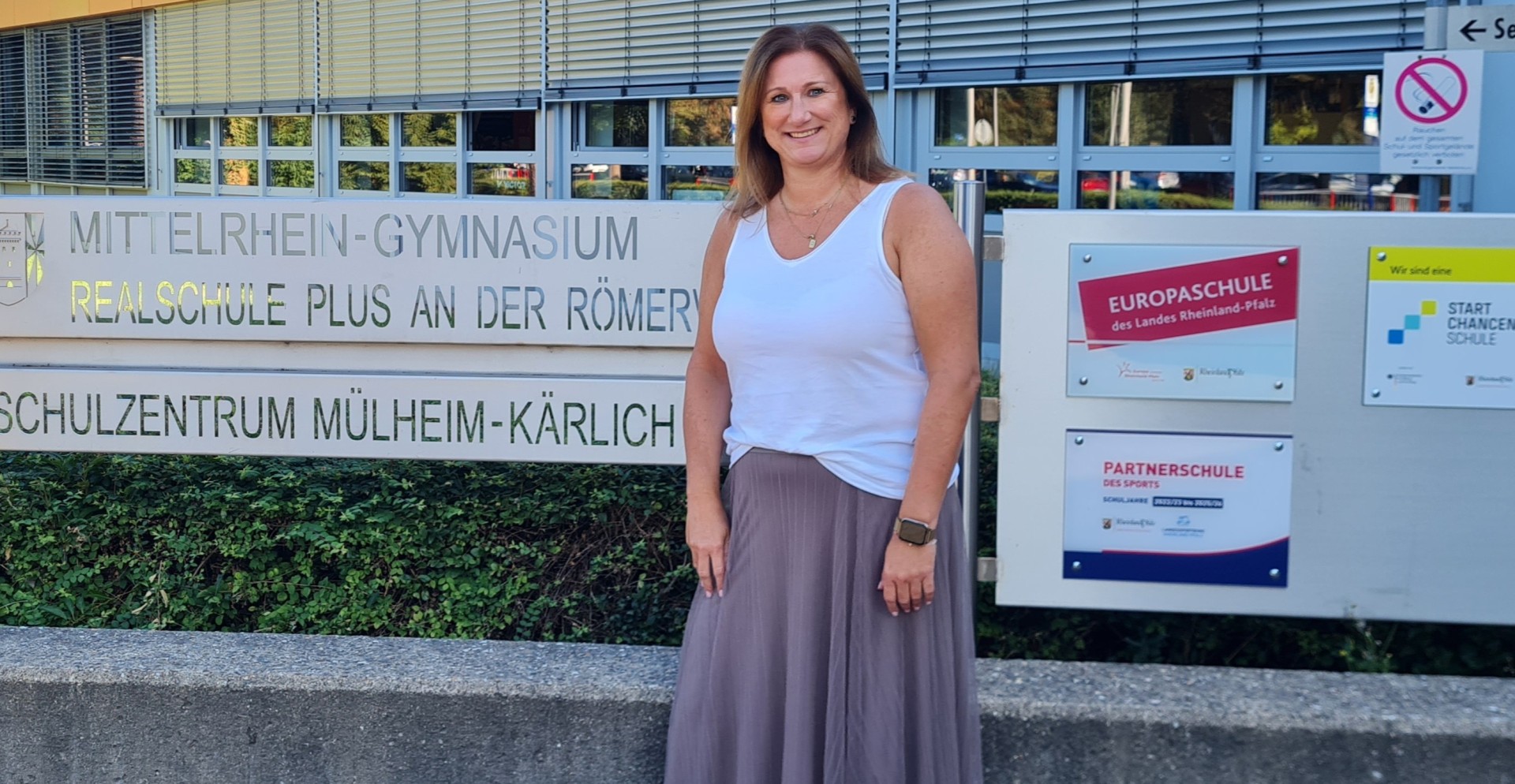 Jobfüxin Katrin Lyding Jobfüxin Katrin Lyding steht an dem Schild des Schulzentrums Mülheim-Kärlich.