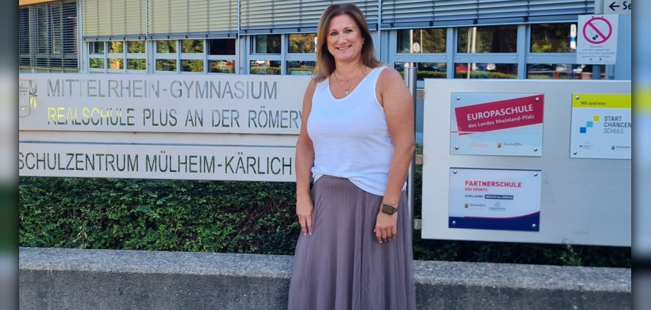 Jobfüxin Katrin Lyding steht an dem Schild des Schulzentrums Mülheim-Kärlich.