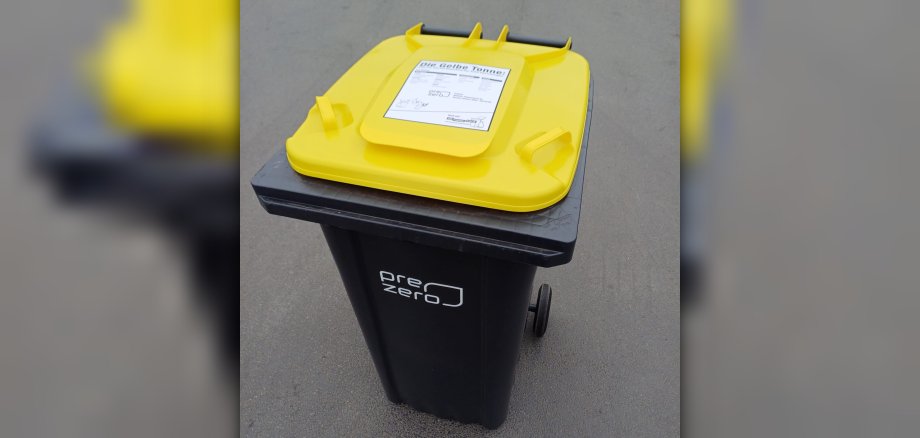 Auf dem gelben Deckel einer schwarzen Mülltonne klebt ein Info-Hinweis zur Befüllung des Behälters.