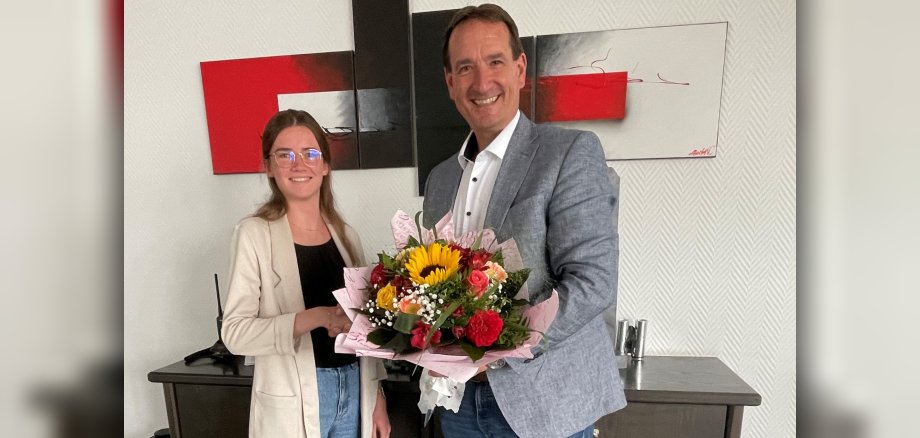 Absolventin Sarah Schiller bekommt von Bürgermeister Thomas Przybylla einen Blumenstrauß überreicht.