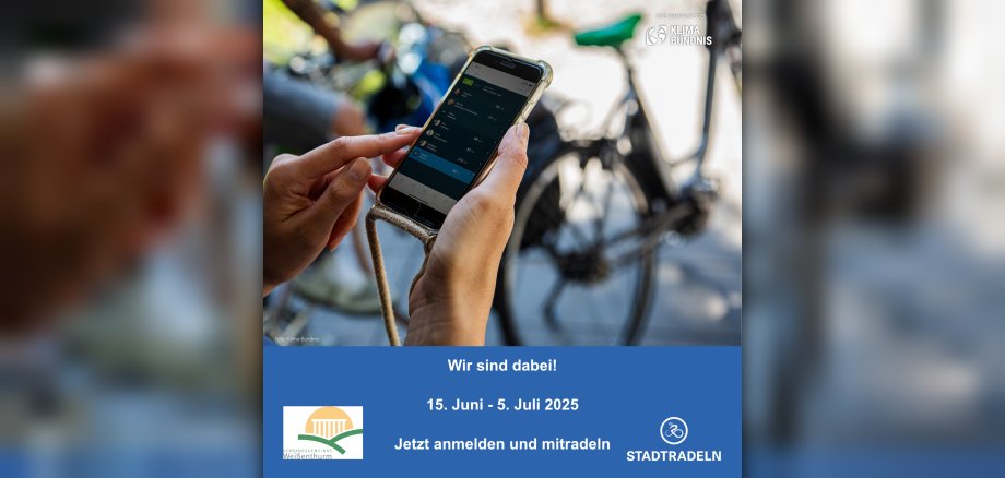 Vor einem Fahrrad im Hintergrund hält eine Person in ihren beiden Händen ein Handy, auf dem die App zum Stadtradeln geöffnet ist.