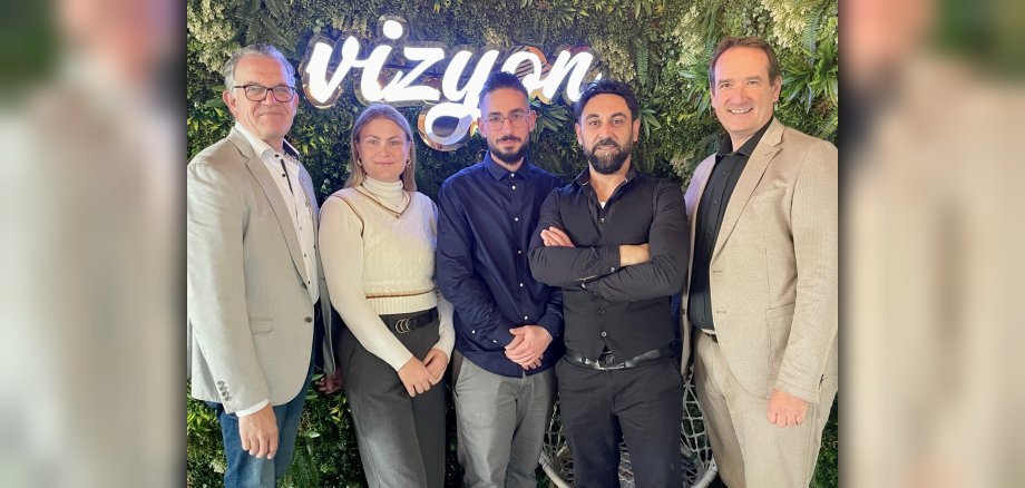 Bürgermeister Thomas Przybylla steht mit Wirtschaftsförderin KIm Lachmann, dem Mülheim-Kärlicher Stadtbürgermeister Gerd Harner und zwei Mitgliedern der Gastronomenfamilie Dal im neu eröffneten Restaurant vor dem Schriftzug Vizyon.