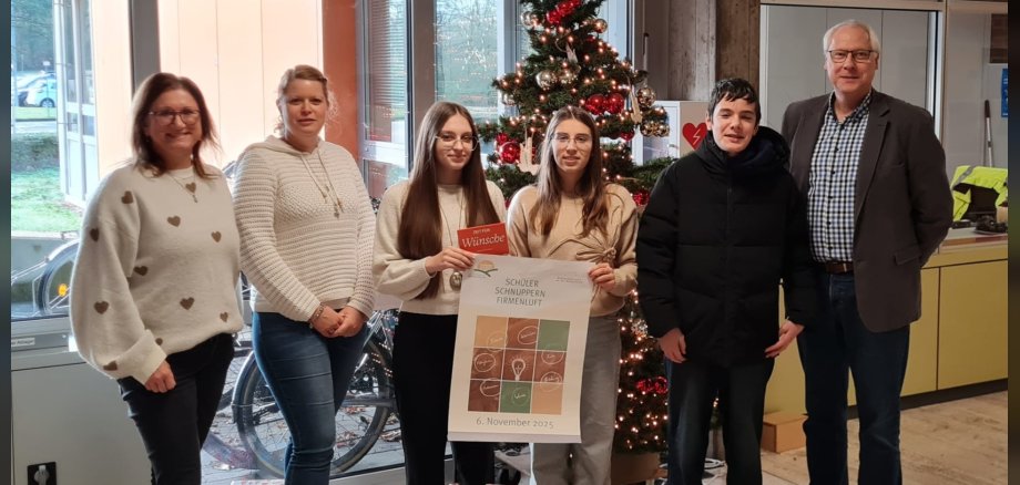 Präsentationen Schüler schnuppern Firmenluft Jobfüxin Katrtin Lyding, Projektbeauftragte Kristina Uerz und Schulleiter Gerhard Müller stehen mit den Schülerinnen und dem Schüler, die den Präsentationswettbewerb gewonnen haben, vor einem Weihnachtsbaum.