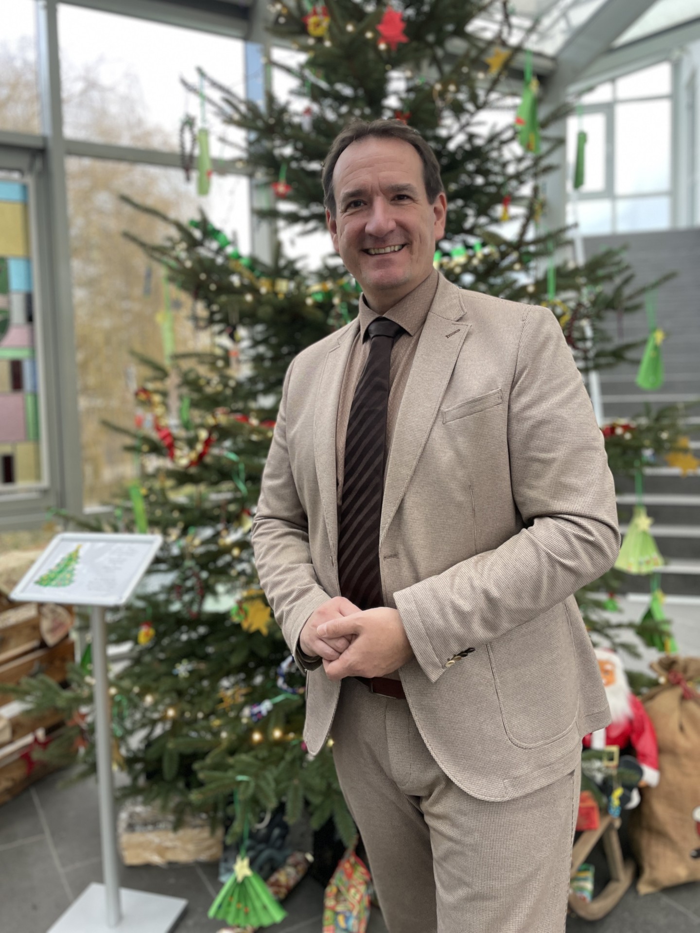 Bürgermeister Thomas Przybylla steht im Foyer des Rathauses vor dem geschmückten Weihnachtsbaum.