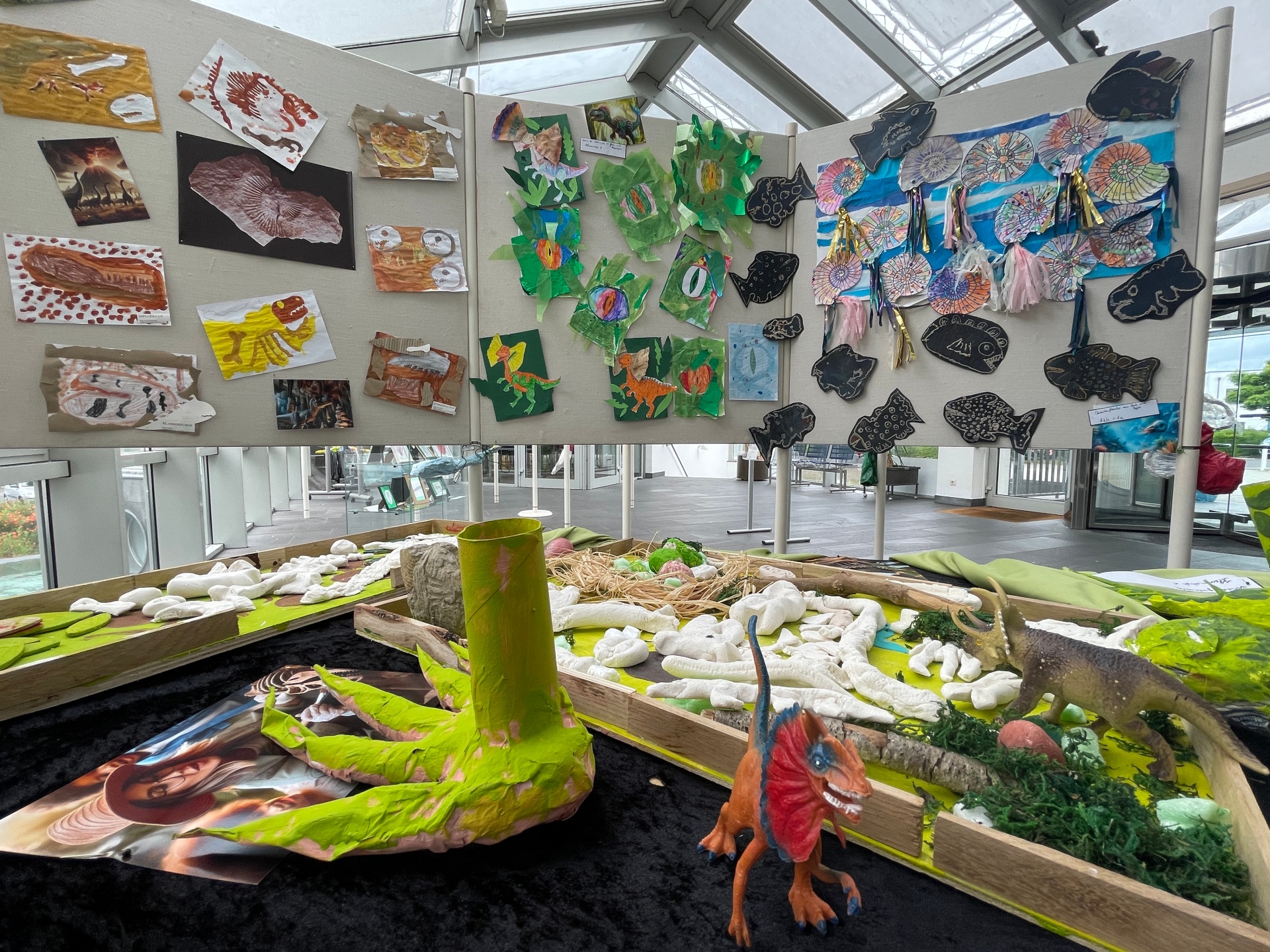 Ausstellung Winzlinge und Giganten Foto 1 Ausstellungsobjekte sind auf einem Tisch im Vordergrund zu sehen, dahinter Bilder an Wänden.