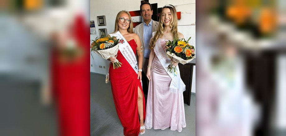 Besuch Majestäten Foto Kirschblütenkönigin Annemarie I. und Blütenkönigin Victoria I. stehen jeweils mit einem Blumenstrauß mit Bürgermeister Thomas Przybylla in dessen Büro.