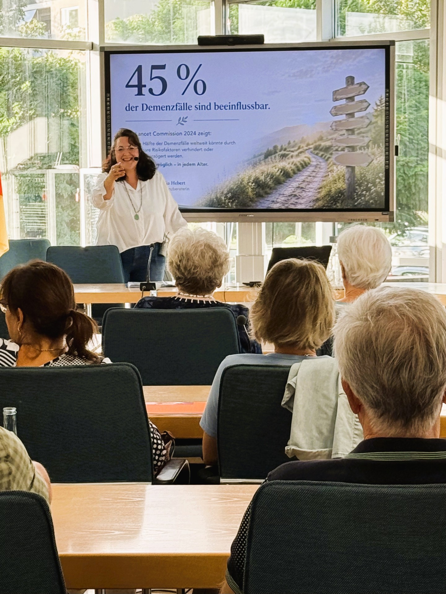 Vortrag Demenzprävention Referentin Nadja Hebert steht vor ihrer Präsentation und spricht zum Publikum