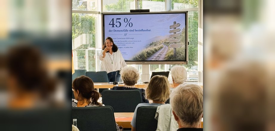 Vortrag Demenzprävention Referentin Nadja Hebert steht vor ihrer Präsentation und spricht zum Publikum