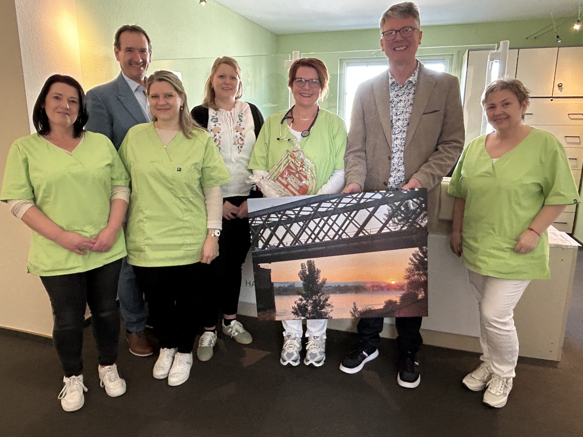 Die neue Urmitzer Hausärztin Dr. Monika Jaekel steht mit VG-Bürgermeister Thomas Przybylla, dem Urmitzer Ortsbürgermeister Norbert Bahl, Kristina Uerz von der Wirtschaftsförderung und dem Praxisteam am Empfang. 