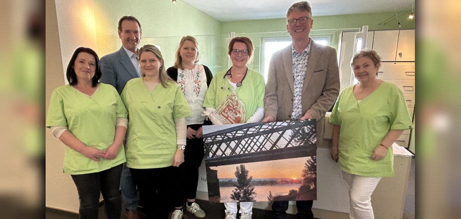 Die neue Urmitzer Hausärztin Dr. Monika Jaekel steht mit VG-Bürgermeister Thomas Przybylla, dem Urmitzer Ortsbürgermeister Norbert Bahl, Kristina Uerz von der Wirtschaftsförderung und dem Praxisteam am Empfang. 