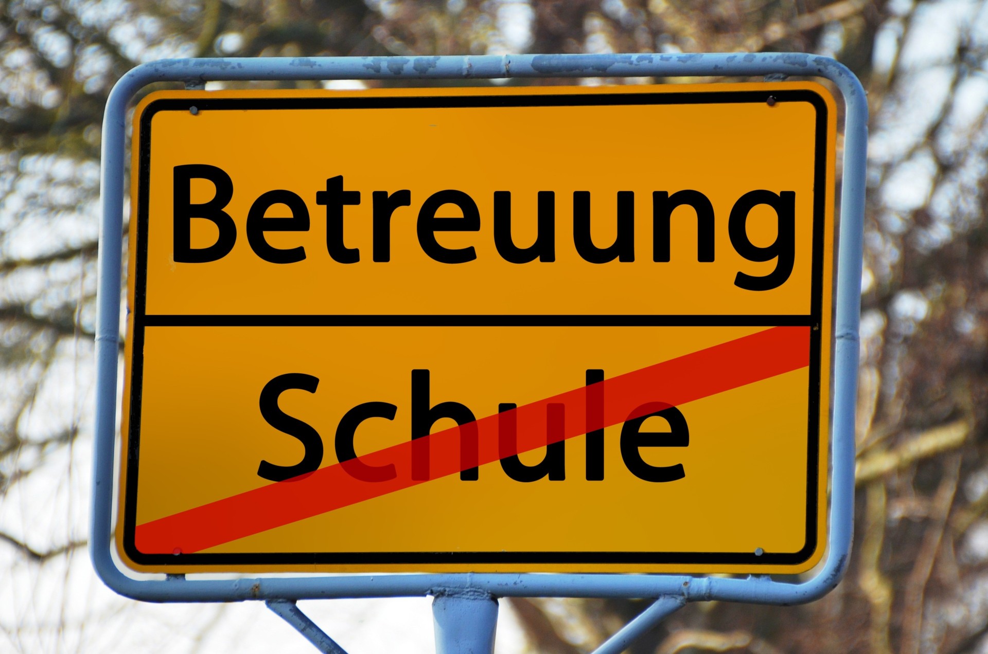 Betreuung Schulkinder Ein gelbes Schild wie Ortsschilder am Straßenrand trägt oben die Beschriftung "Betreuung", darunter rot durchgestrichen das Wort "Schule".