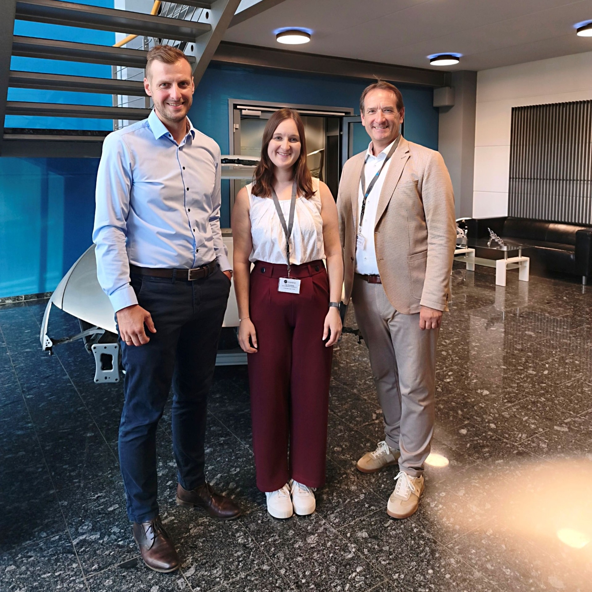 Besuch Laserline Foto Laserline-Geschäftsführer Alexander Arndt steht mit Wirtschaftsförderin Alina Kneip und VG-Bürgermeister Thomas Przybylla im Eingangsbereich des Unternehmens.