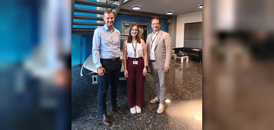 Besuch Laserline Foto Laserline-Geschäftsführer Alexander Arndt steht mit Wirtschaftsförderin Alina Kneip und VG-Bürgermeister Thomas Przybylla im Eingangsbereich des Unternehmens.