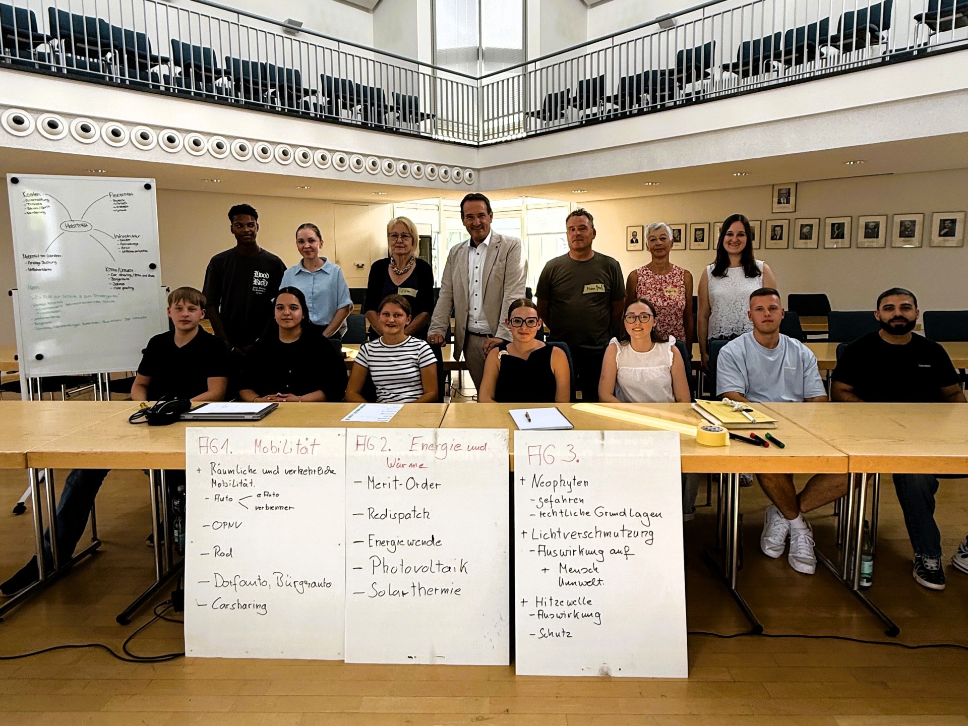 Azubi-Workshops Klimabeirat Die Azubis der VG sitzen im Ratssaal, dahinter stehen Bürgermeister Przybylla und drei Vertreter des Klimabeirats neben einem Flipchart mit Themen.