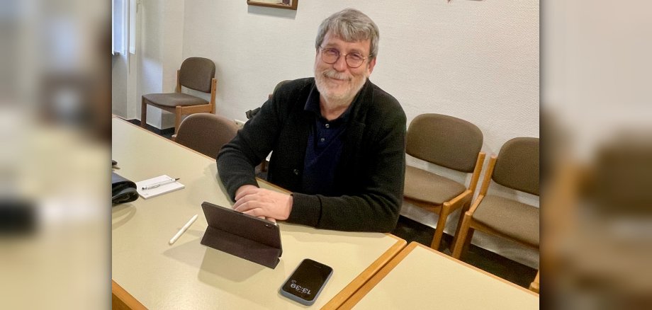 Digitalbotschafter Ingo Neumann sitzt vor einem Tablet an einem Tisch, neben ihm ein Smartphone.