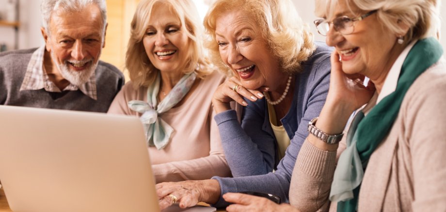Digitalbotschafter Drei ältere Frauen und ein älterer Mann sitzen vor einem aufgeklappten Laptop.