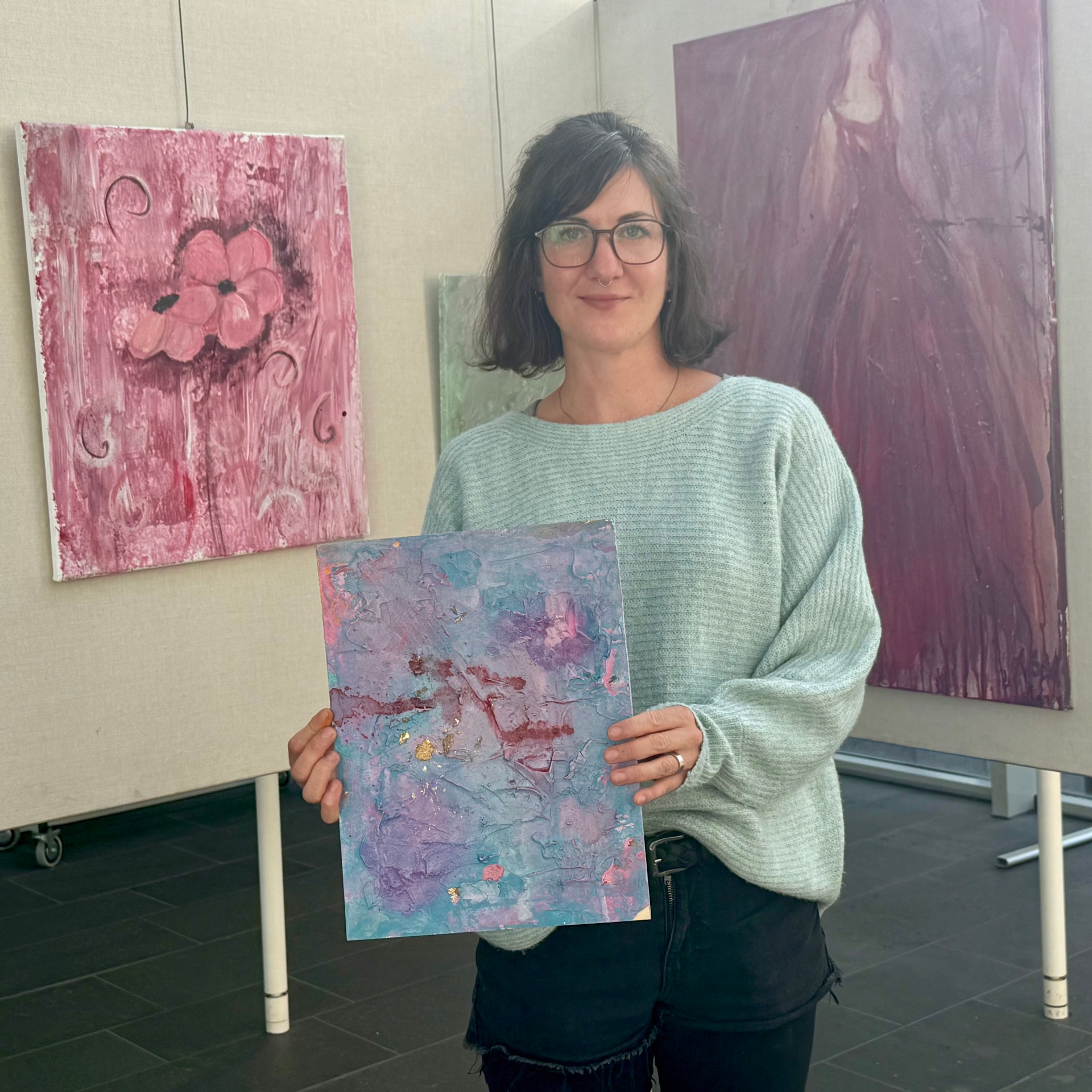 Ausstellung Poesie in Pastell Foto Die Künstlerin Annika Hill steht mit einem ihrer Bilder vor Ausstellungswänden mit ihren Werken im Foyer des VG-Rathauses.
