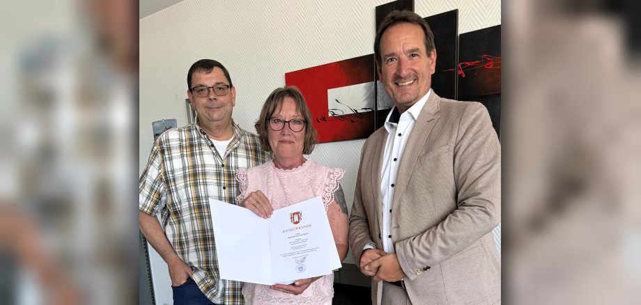 Ruth Kreuter-Perscheid steht zwischen Bürgermeister Przybylla und dem Vorsitzenden des Personalrats, Marko Röser, mit ihrer Urkunde.