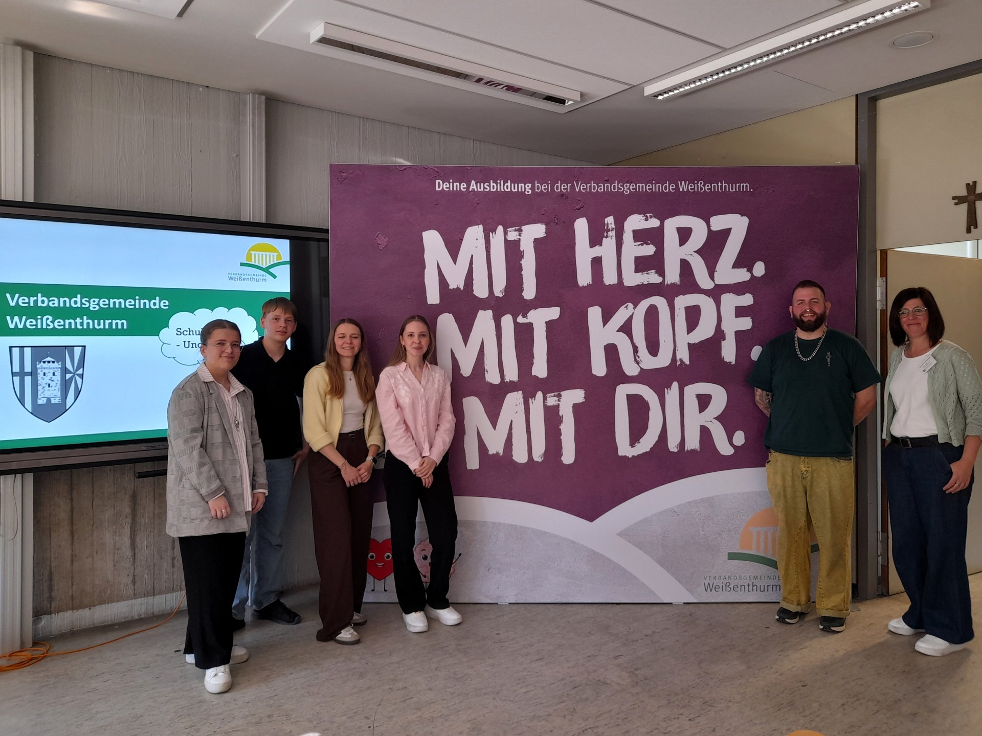 Vor dem Banner der VG stehen die Kolleginnen und Kollegen, die die Verwaltung präsentiert haben.